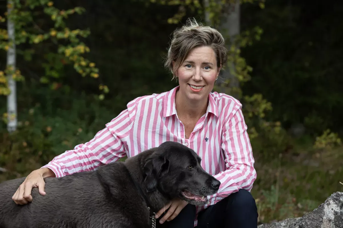Författaren barnboken Ina och Isbjörnsklubben, Johanna Flood, sitter tillsammans med en hund. 